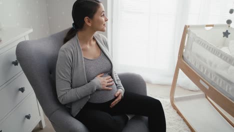 Frau-In-Fortgeschrittener-Schwangerschaft-Sitzt-Im-Sessel-Und-Streichelt-Ihren-Bauch.