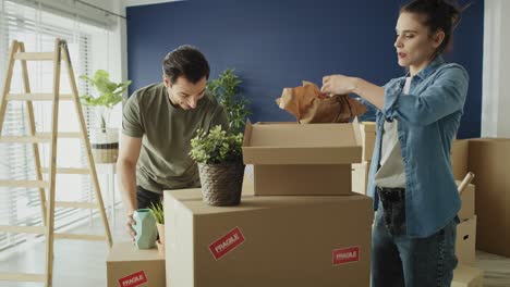 Video-of-couple-packing-things-to-boxes-while-moving-house.