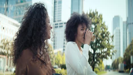 Video-Von-Zwei-Glücklichen-Geschäftsfrauen,-Die-Mit-Einer-Tasse-Kaffee-Spazieren-Gehen