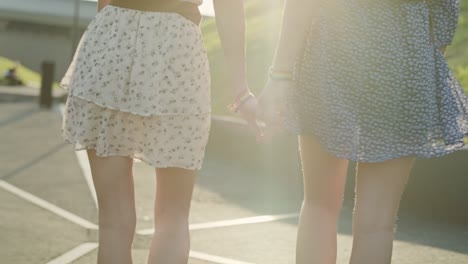 Handheld-video-of-two-unrecognizable-women-walking-and-holding-hands