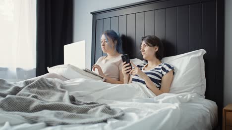 Handheld-Video-Von-Frauen,-Die-Den-Morgen-Mit-Technologie-Im-Bett-Verbringen.