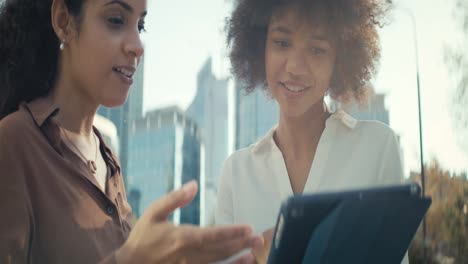 Tilt-up-video-of-businesswomen-discussing-with-digital-outdoors