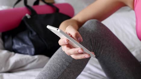 Female-athlete-using-mobile-phone-in-bed