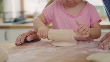 Handheld-view-of-child-rolling-dough-in-the-kitchen