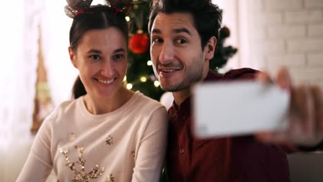 Vista-Portátil-De-Una-Pareja-Juguetona-Haciendo-Un-Selfie-En-Navidad