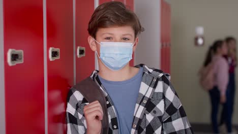 Video-portrait-of-smiling-teenager-in-protective-face-mask-at-school