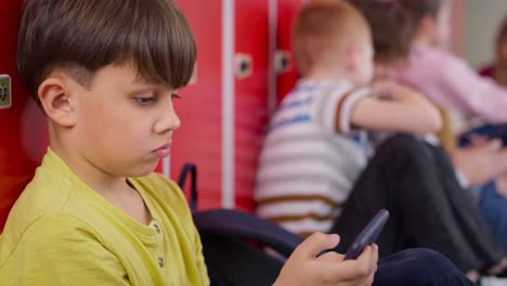 Close-up-video-of-schoolboy-using-smartphone-in-school-corridor
