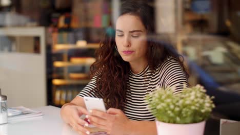 Frau-Benutzt-Ein-Mobiltelefon-Und-Isst-Kuchen-Im-Café