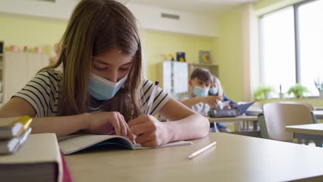 Video--of-schoolgirl-in-protective-mask-writing-in-notebook