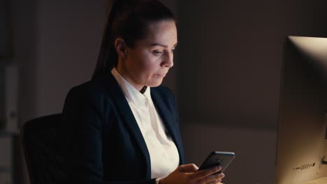 Kaukasische-Erwachsene-Geschäftsfrau,-Die-Zu-Spät-Im-Büro-Arbeitet-Und-Ihr-Mobiltelefon-Benutzt