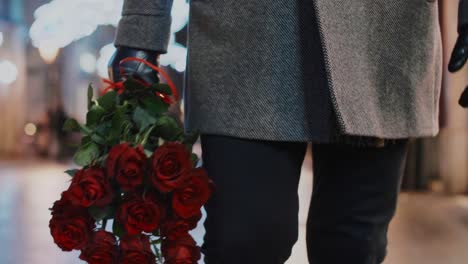 Low-section-of-man-holding-a-bunch-of-red-roses