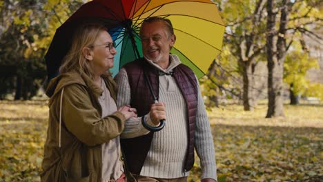 Senior-caucasian-couple-with-colourful-umbrella-at-park