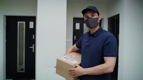 Video-portrait-of-courier-in-protective-mask-holding-package