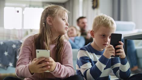 Children-using-mobile-phone-in-living-room