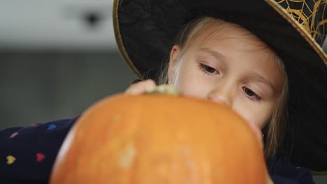 Little-girl-in-witch-costume-drawing-on-pumpkin