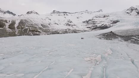 Aerial-panoramic-landscape-view-of-people-hiking-on-the-ice-surface-of-Virkisjokull-glacier,-Iceland
