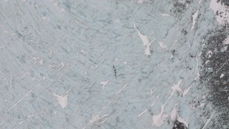 Aerial-top-view-of-people-hiking-on-the-ice-surface-of-Virkisjokull-glacier,-Iceland