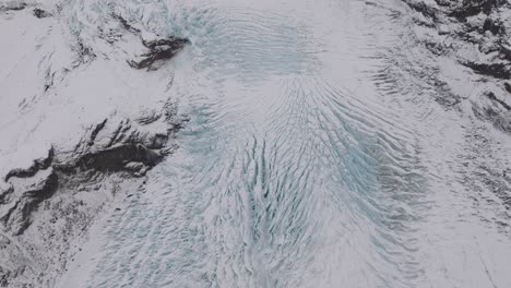 Aerial-landscape-view-over-ice-cracks-and-formations-in-Virkisjokull-glacier-covered-in-snow,-Iceland