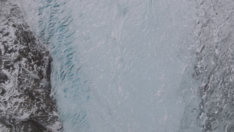 Aerial-top-view-over-ice-formations-in-Virkisjokull-glacier-covered-in-snow,-Iceland