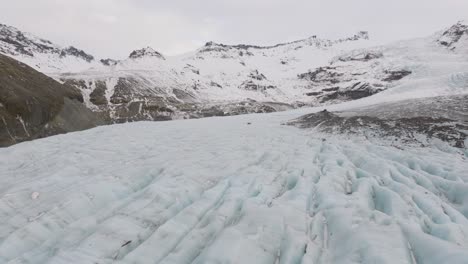 Aerial-panoramic-landscape-view-over-ice-cracks-and-formations-in-Virkisjokull-glacier-covered-in-snow,-Iceland