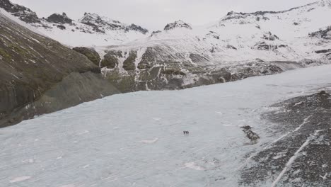 Vista-Aérea-Del-Paisaje-De-Personas-Caminando-Sobre-La-Superficie-De-Hielo-Del-Glaciar-Virkisjokull,-Islandia