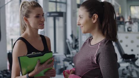 Fitness-instructor-and-woman-chatting-before-gym-session
