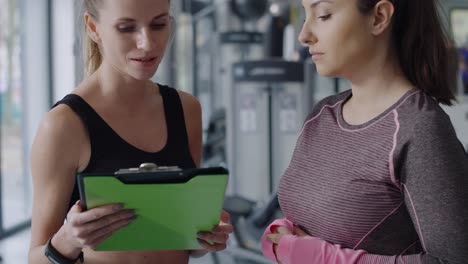 Tilt-up-video-shows-of-instructor-and-woman-talking-at-gym