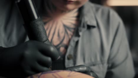 Focus-woman-tattooing-arms-of-her-customer.