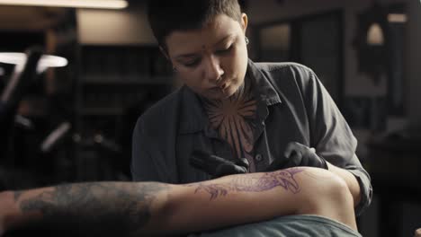 Adult-caucasian-woman-tattooing-arms-of-her-customer.
