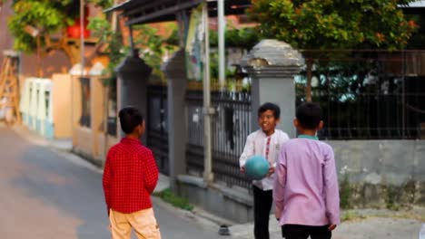 Niedliche-Kleine-Kinder,-Die-Im-Sommer-Draußen-Auf-Der-Straße-Eines-Wohnkomplexes-In-Indonesien-Gemeinsam-Fußball-Spielen