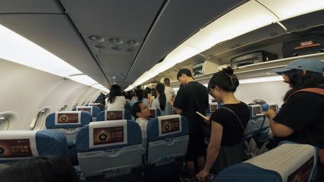 Asian-passengers-standing-in-airplane-walk-way-aisle-waiting-for-disembarkation