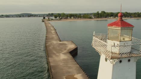 Toma-De-Respaldo-Con-Drones-Pasando-Por-El-Pequeño-Faro-En-Sodus-Point,-Lugar-De-Vacaciones-En-Nueva-York-En-La-Punta-De-La-Tierra-A-Orillas-Del-Lago-Ontario.