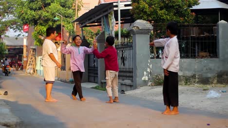 Niedliche-Kleine-Kinder,-Die-Im-Sommer-Draußen-Auf-Der-Straße-Eines-Wohnkomplexes-In-Indonesien-Gemeinsam-Fußball-Spielen