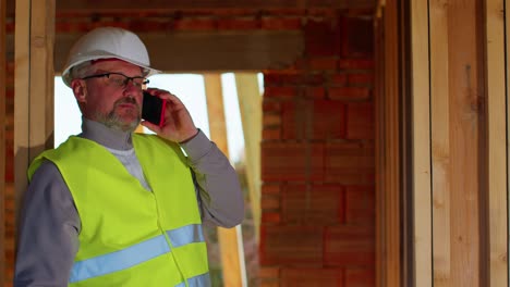 Civil-engineer-architect-specialist-talking-on-mobile-phone-to-control-working-at-construction-site