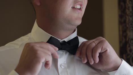 Groom-man-adjusts-bow-tie,-preparing-to-go-to-the-bride,-businessman-in-white-shirt,-wedding-day