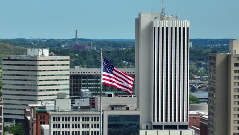 American-flag-waving-in-front-of-Cedar-Rapids,-IA-skyline