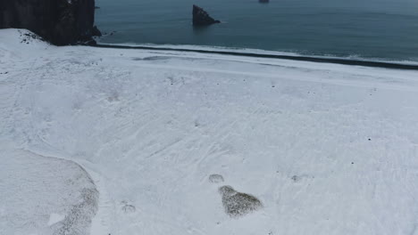Luftaufnahme-Mit-Neigung-Zu-Einem-Schwarzen-Sandstrand,-Wintertag-An-Der-Küste-Islands