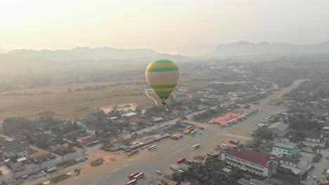 Low-flying-hot-air-balloon-above-Vang-vieng-Laos-with-golden-light,-aerial