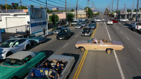 Vista-Aérea-Siguiendo-A-Viejos-Lowriders-En-Las-Calles-De-La-Soleada-Ciudad-De-Los-Ángeles,-EE.UU.