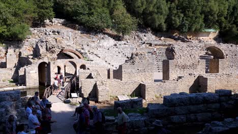 Stone-Walls-of-Buildings-and-the-Roman-Amphitheater-in-Ancient-Butrint-City,-Albania,-Tourists-Visiting-Architectural-Marvels