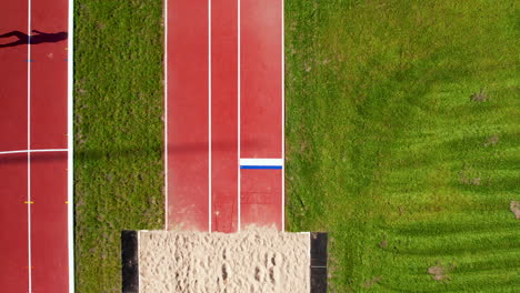 Luftaufnahme-Von-Oben-Nach-Unten-–-Laufstrecke,-Die-Zum-Weitsprung-Sandkasten-In-Einem-Leichtathletikstadion-Führt