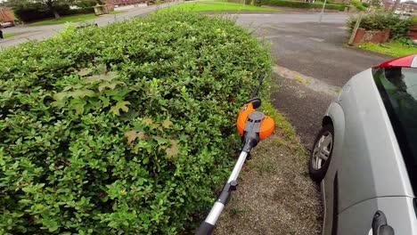 POV-male-doing-chores-clipping-overgrown-hedge-maintenance-with-electrical-garden-shears