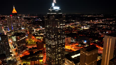 Vuelo-Aéreo-De-La-Torre-Truist-Plata-Y-La-Magnífica-Iluminación-De-La-Ciudad-De-Atlanta-A-Medianoche