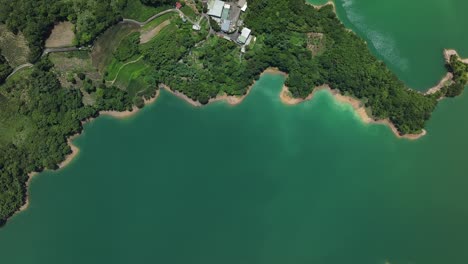 Aerial-top-down-of-sandy-shore-with-green-water-between-hills-during-sunny-day---Feitsui-Reservoir-in-Taiwan
