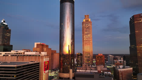 Aerial-approaching-shot-of-Westin-Peachtree-Plata-Tower-with-sunset-reflection-on-mirrored-windows-in-Atlanta