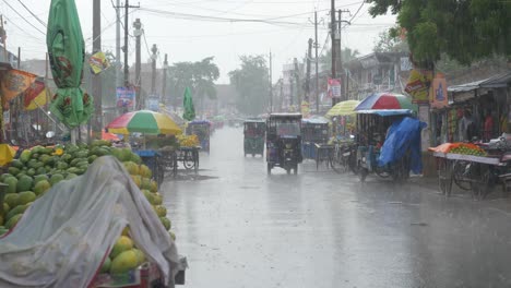 Heavy-rainfall-after-intense-heat-wave-in-rural-Indian-town,-Street-vendors-on-road