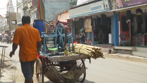 Midday-heat-wave-in-northern-India,-Indian-man,-sugar-cane-juice-seller-wiping-off-sweat-on-his-face-during-intense-summer-heat