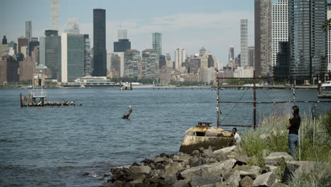 Dos-Adultos-Jóvenes-Contemplan-El-Horizonte-De-Manhattan-Desde-El-Paseo-Marítimo-De-Brooklyn,-Nueva-York