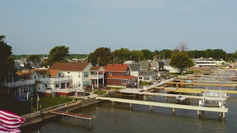 Drohnenaufnahme-Der-Strandhäuser,-Docks,-Boote-Und-Flaggen-Am-Urlaubsort-Sodus-Point,-New-York,-An-Der-Landspitze-Am-Ufer-Des-Lake-Ontario