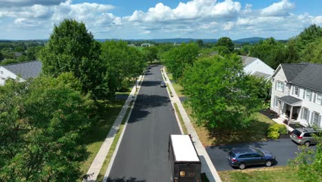 UPS-delivery-man-entering-United-Parcel-Service-truck-after-dropping-off-package-at-large-American-home-in-neighborhood